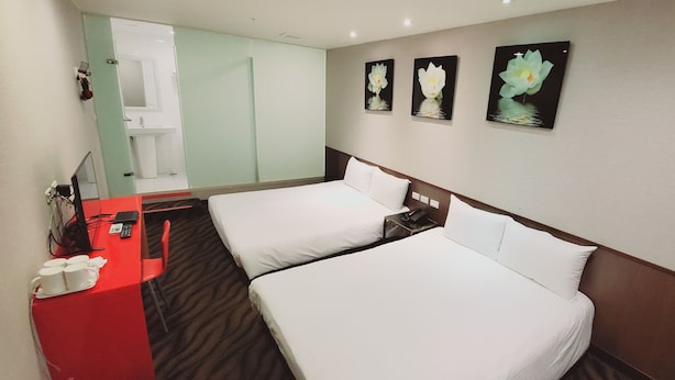 A hotel room with two beds, a desk with a telephone, and a mirror. - Ximen Garden Hotel (Taipei)