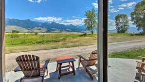 A patio with wooden chairs and a table, overlooking a scenic landscape with mountains and trees. - Dreamy Mountain-View Cabin Near Yellowstone! (Livingston)