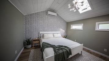 A bedroom with a bed, a window, a ceiling fan, and a potted plant.