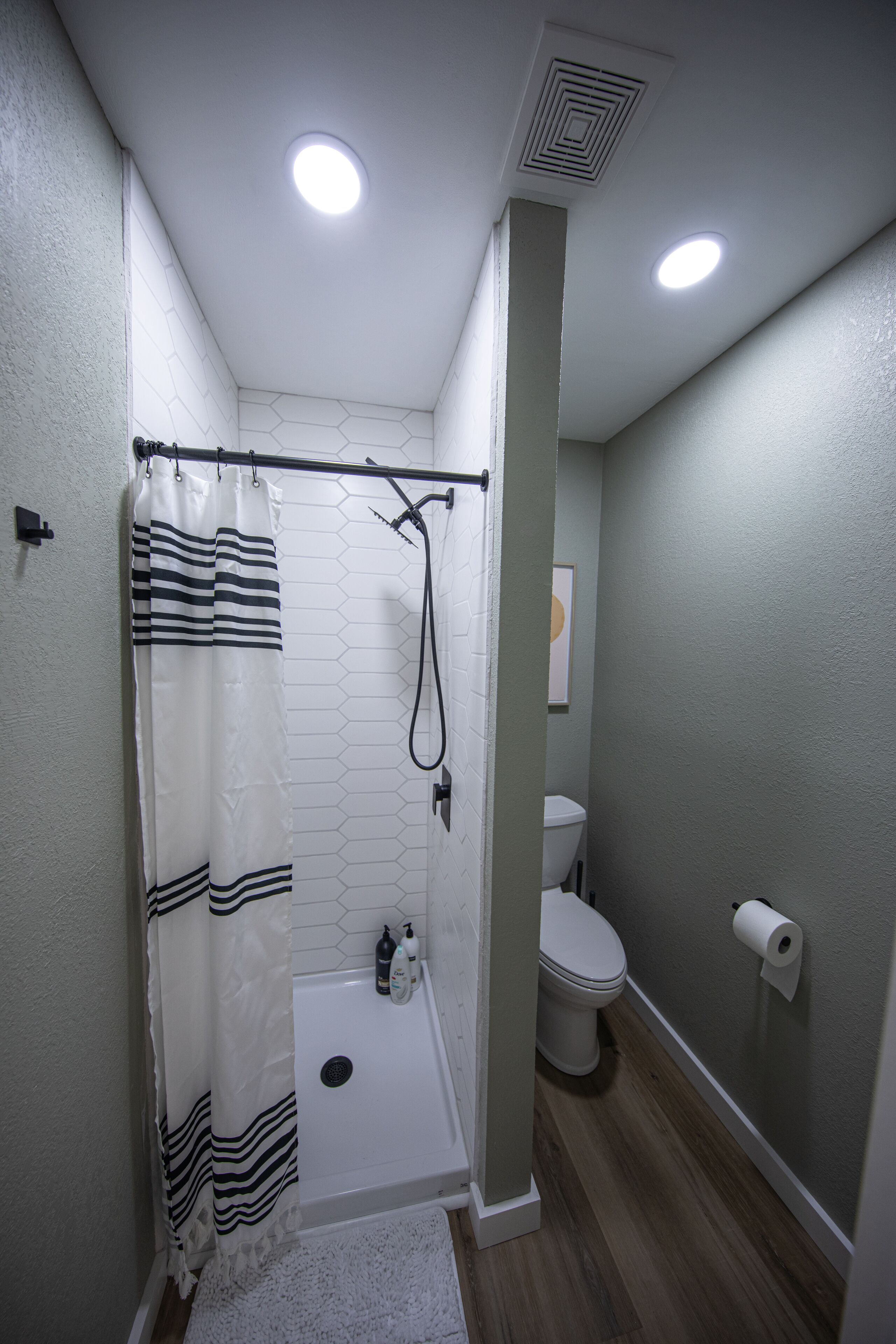 A bathroom with a shower, toilet, and a white sink.