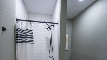 A bathroom with a shower, toilet, and a white sink.