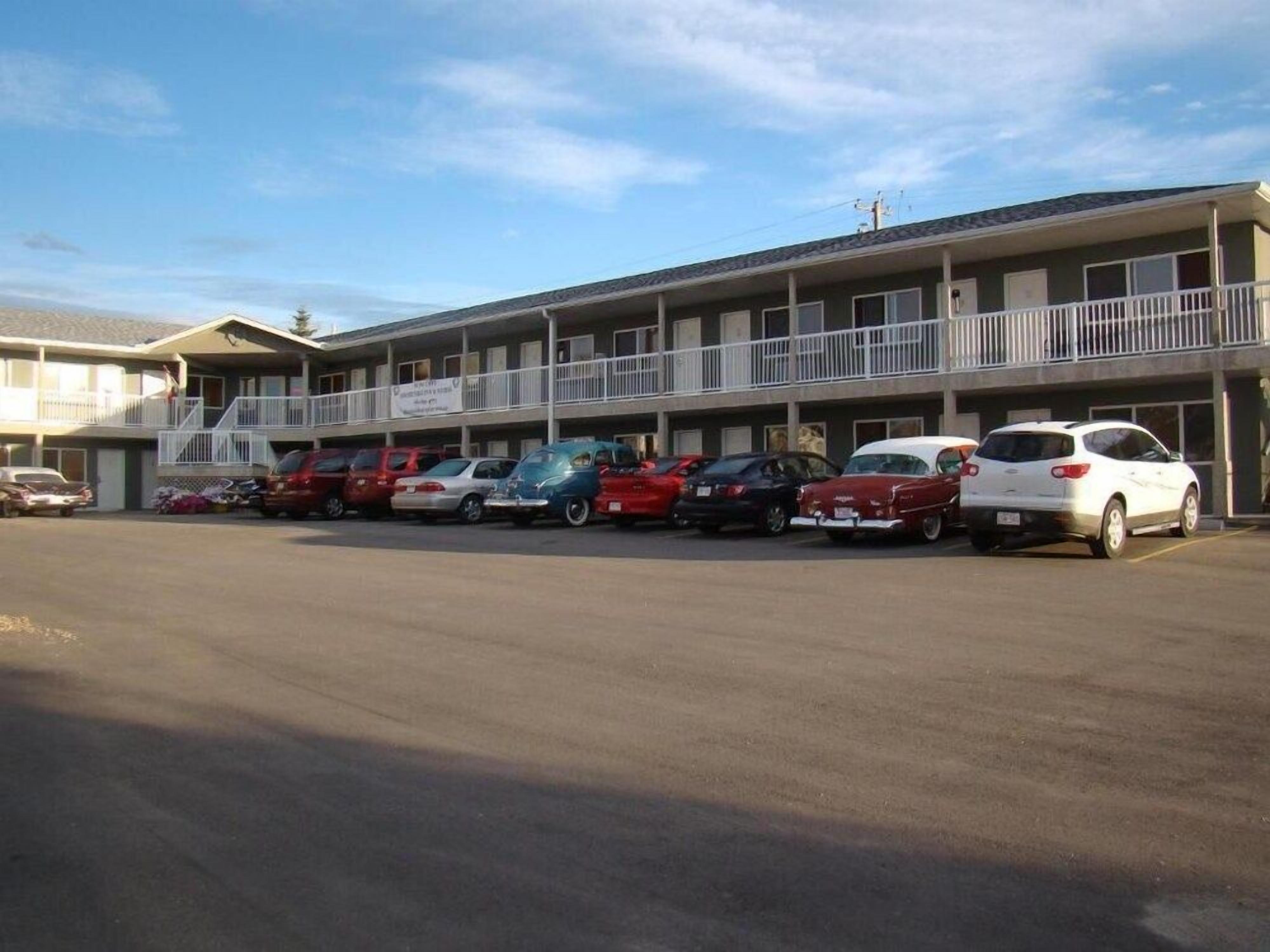 Un motel con múltiples espacios de estacionamiento y un edificio de dos pisos con balcones.