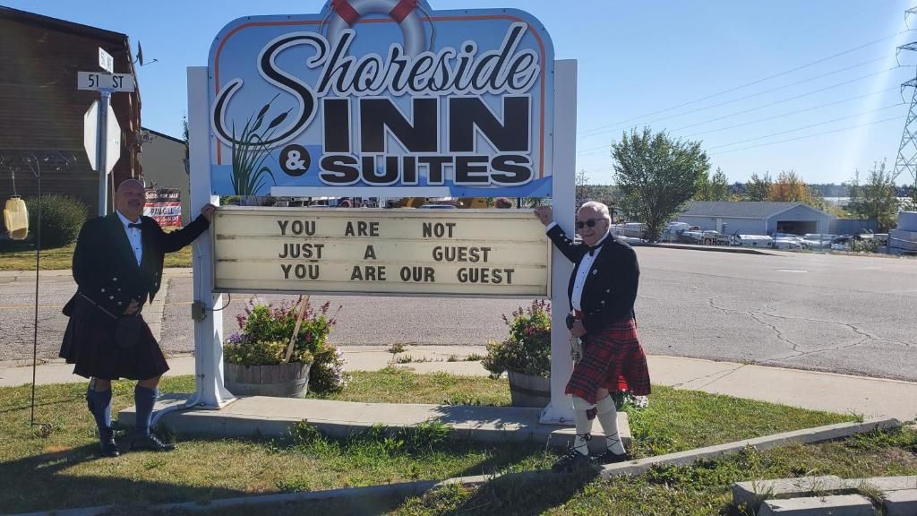 Een bord voor Shoreside Inn & Suites met een prikbord waarop staat: 'JE BENT GEEN KLANT, MAAR EEN GAST'.