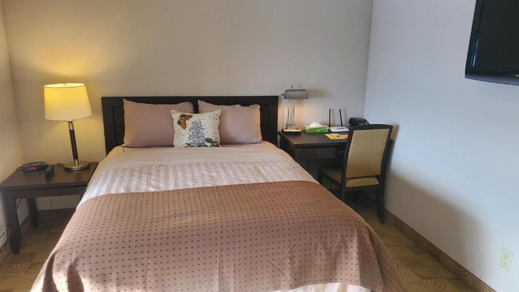 Ein Hotelzimmer mit einem Bett, Nachttischen, einem Schreibtisch und einem Stuhl.