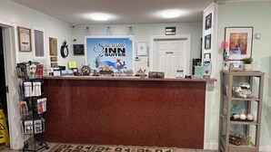 A reception desk with a 'Shoreline Suites' sign, a clock, and various informational signs. - Shoreside Inn & Suites (Wabamun)