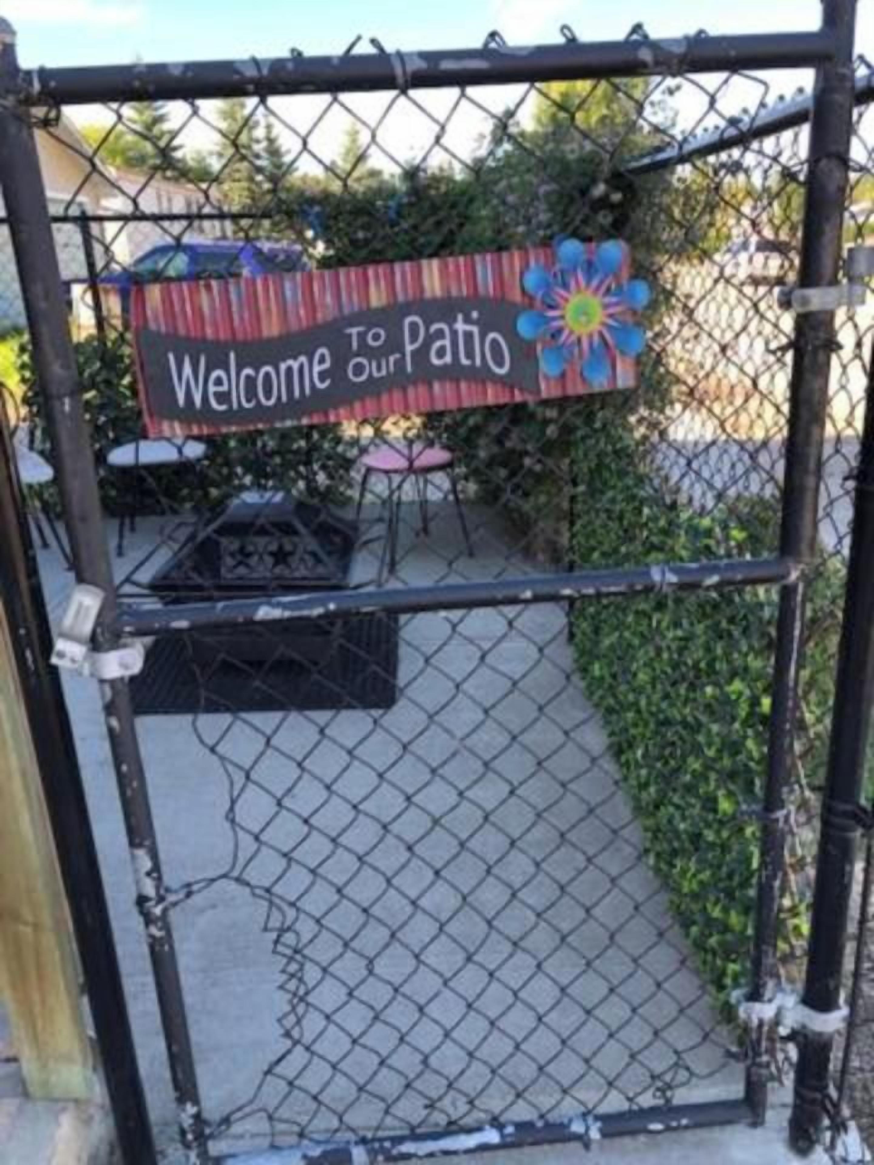 A chain-link fence with a sign that reads 'Welcome to Patio.'