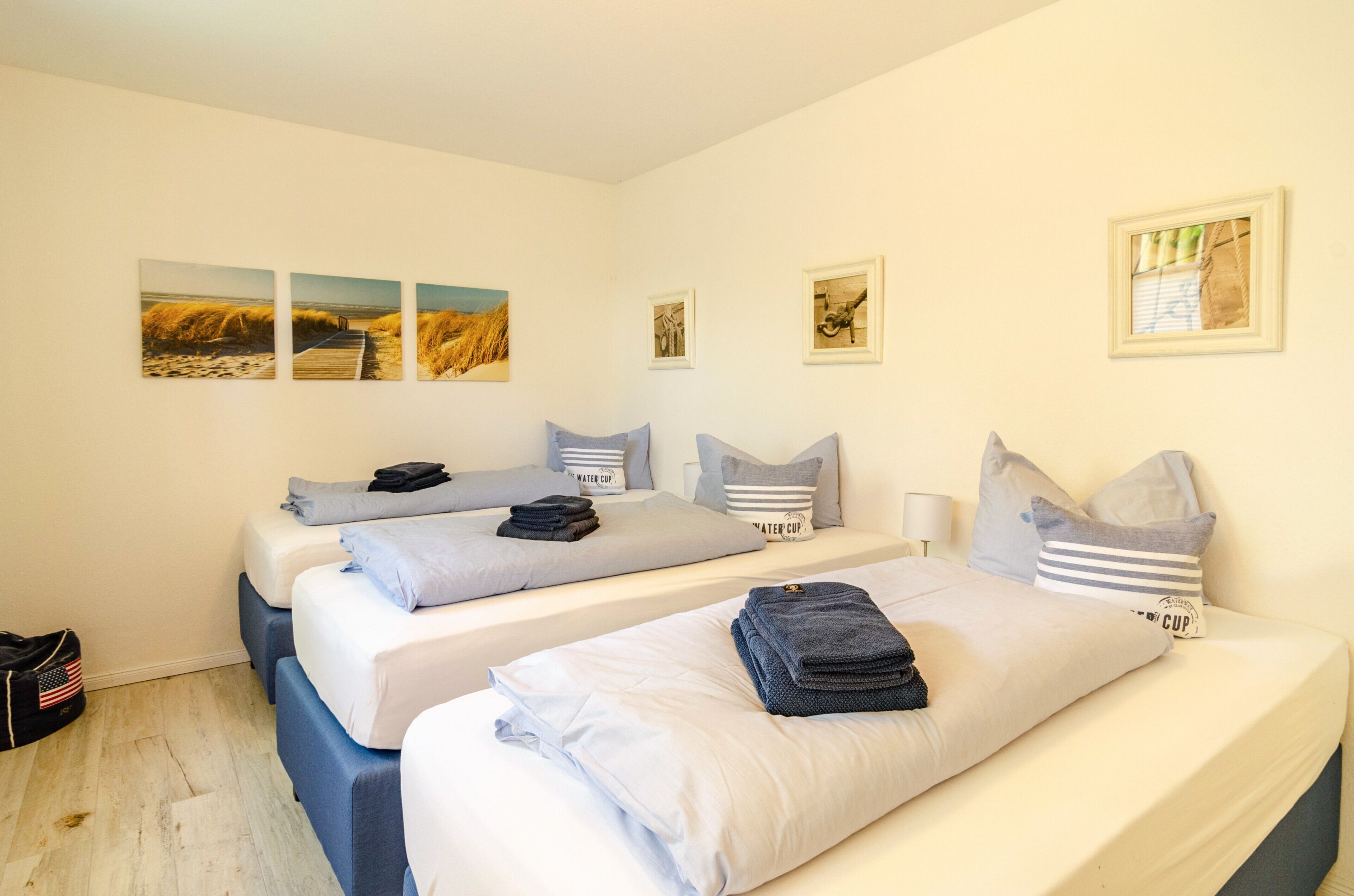 Une chambre d’hôtel avec deux lits, une petite table et des œuvres d’art accrochées au mur.