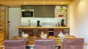 A compact kitchen with a central island, wooden ceiling, and a dining area with a table set for four. - Grand Roc A216 150m from Slopes, Mont-Blanc View & Parking, Argentière (Chamonix), France (Argentière (Chamonix))