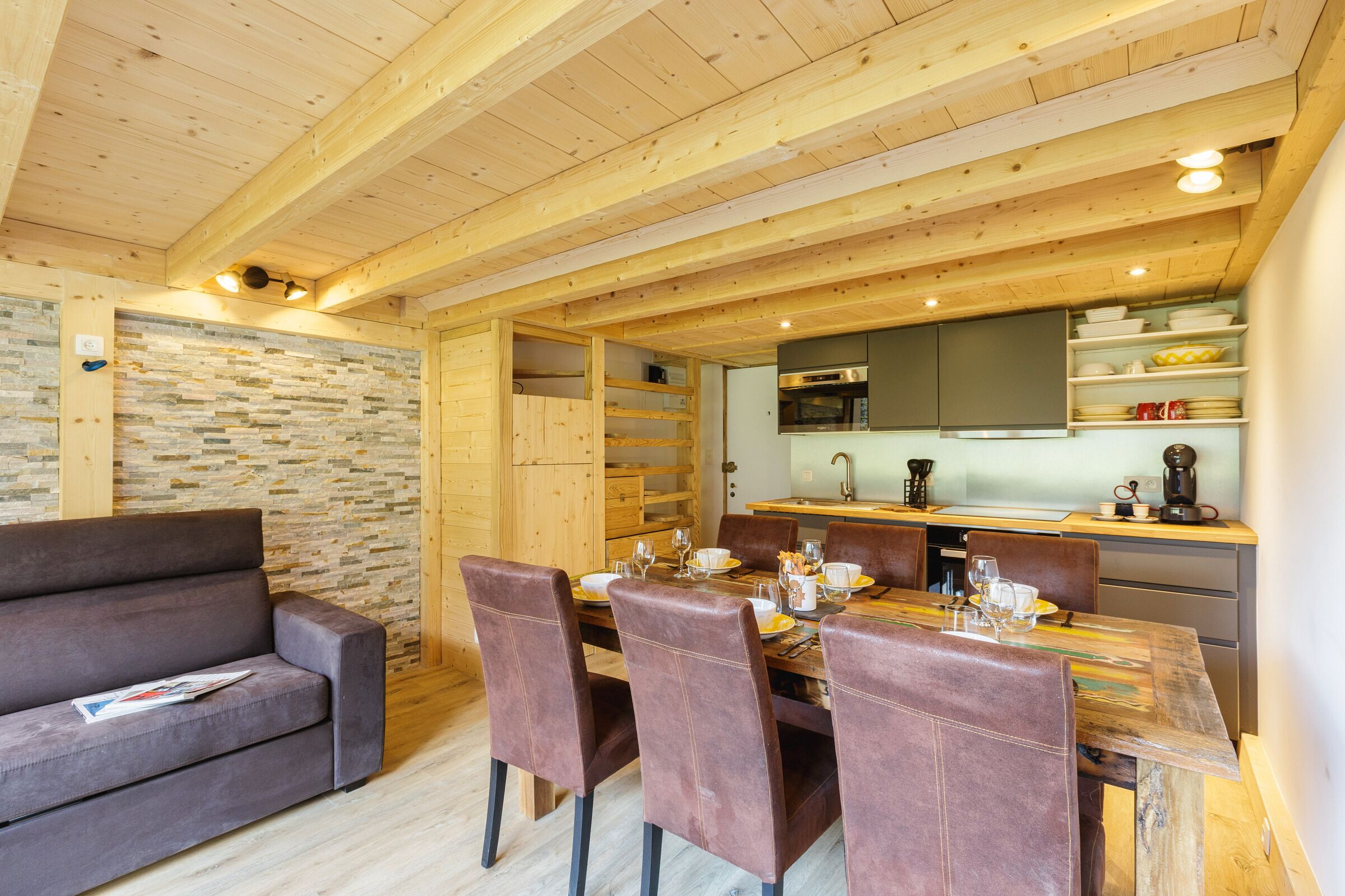 Um interior acolhedor em madeira com espaço de refeições, sofá e cozinha.