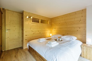 A wooden-paneled room with a bed, a bedside table, and a window.