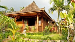 A traditional wooden house with a tiled roof, surrounded by lush greenery and palm trees. - Vinarya Villa (Tegallalang)