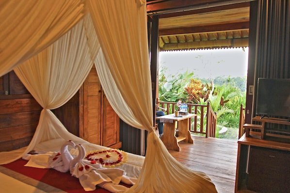 A bedroom with a canopy bed, wooden furniture, and a view of the outdoors.