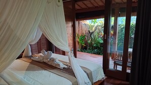 A bedroom with two beds, a wooden floor, and a view of a garden through an open door. - Vinarya Villa (Tegallalang)