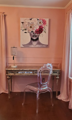 A room with a desk, a chair, and a painting on the wall.