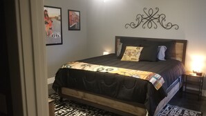 A bedroom with a bed, a nightstand, a wall clock, and two framed pictures. - New 1 bedroom cottage right off Route 66. (Galena)