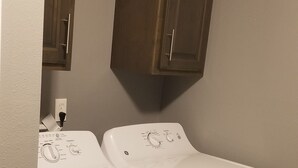 A laundry room with two front-loading washing machines and a cabinet above them. - New 1 bedroom cottage right off Route 66. (Galena)