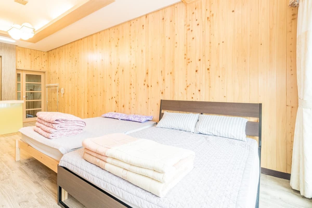 Quarto com parede de madeira, uma cama com almofadas, uma mesinha de cabeceira e um espelho.