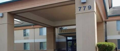 Un edificio con fachada color beige, un acceso cubierto y el número 779.
