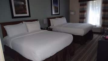 A hotel room with two single beds, a window with curtains, and a framed picture on the wall.