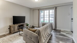 A living room with a flat-screen TV, a sofa, a coffee table, and a patterned rug.