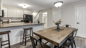 A modern kitchen with white cabinets, a wooden island, and a dining area with a large table and chairs.