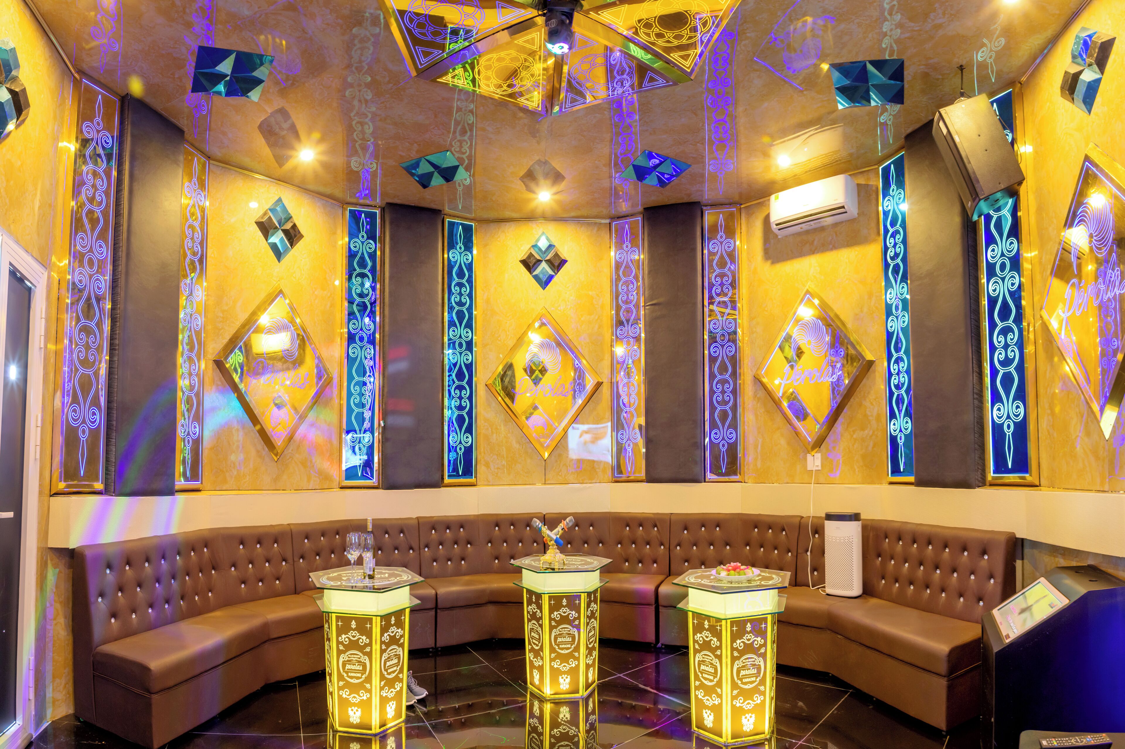 A luxurious room with a curved brown sofa, decorative wall panels, and illuminated geometric patterns.