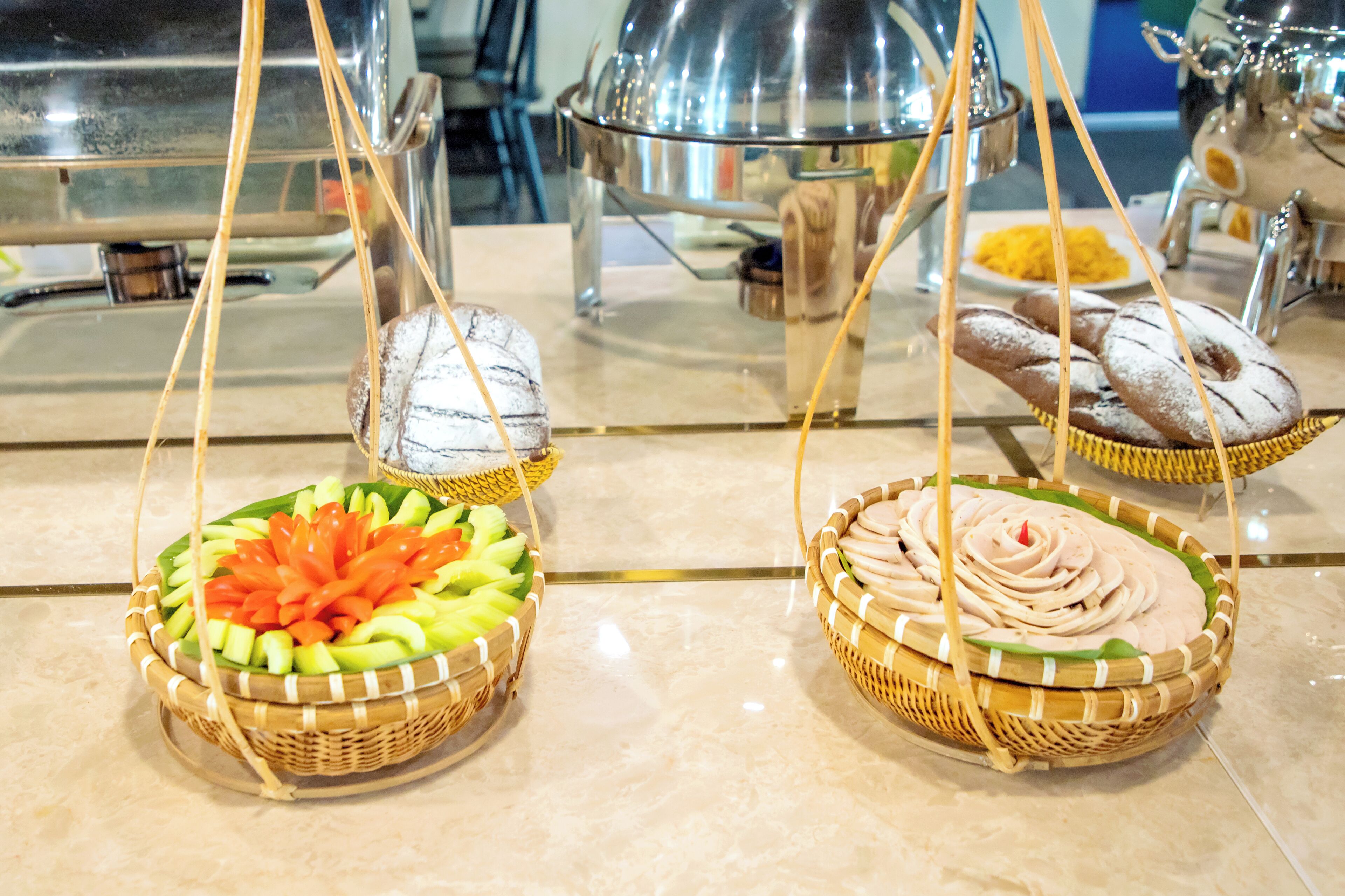 Two wicker baskets with food items on a marble countertop.