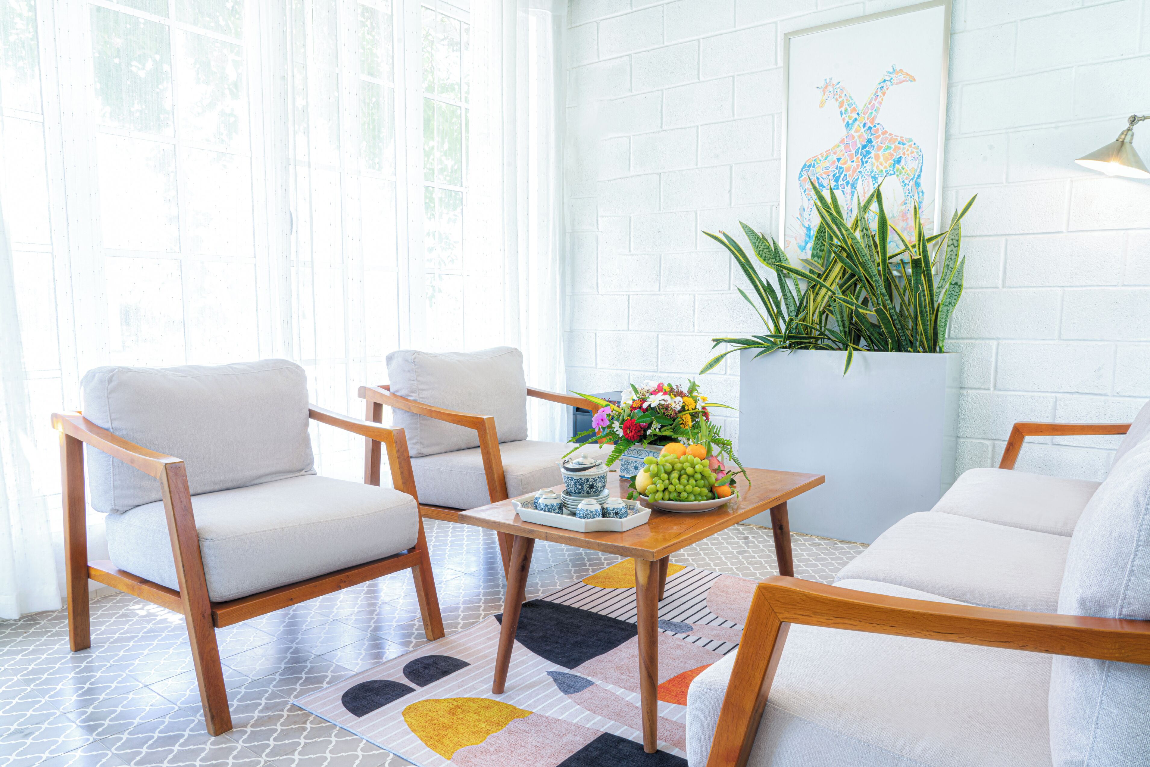 Una habitación luminosa con pared de ladrillo blanco, un ventanal grande y un sofá blanco.