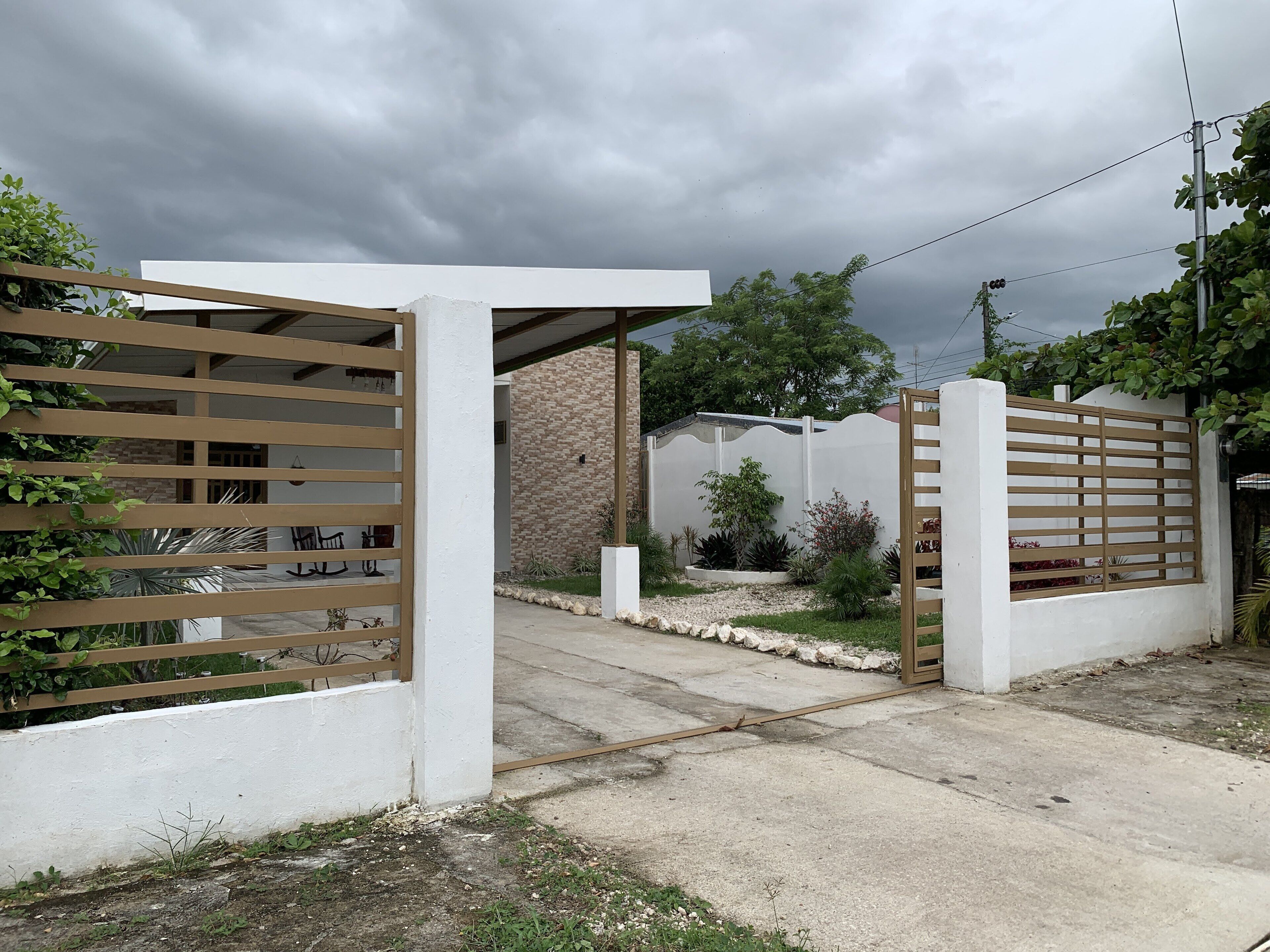 A gated entrance with a concrete pathway leading to a building with a brick facade.