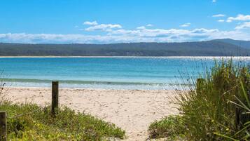 A beach with a clear view of the ocean and distant hills.