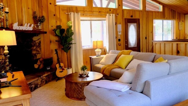 Un salon chaleureux avec une cheminée, un canapé, une table basse et une guitare.