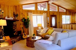 A cozy living room with a fireplace, a sofa, a coffee table, and a guitar.