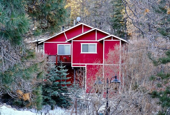 A red cabin with a balcony, surrounded by trees and snow. - Hot Tub,Walk To Bear MTN Ski, Mins to Village (Big Bear Lake)