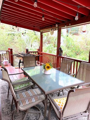 A covered patio with a glass table, wicker chairs, and a sunflower centerpiece. - Hot Tub,Walk To Bear MTN Ski, Mins to Village (Big Bear Lake)
