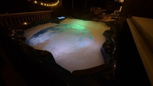 A hot tub with a wooden deck and a string of lights.