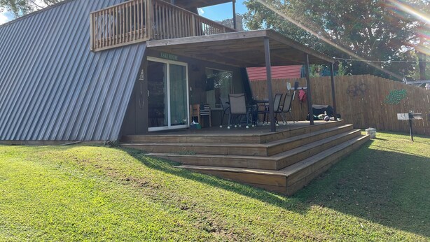 A modern, single-story building with a covered patio area, a deck, and a glass door entrance.