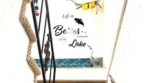A staircase with a decorative wall featuring a fish and the text "Life is Better at the Lake."