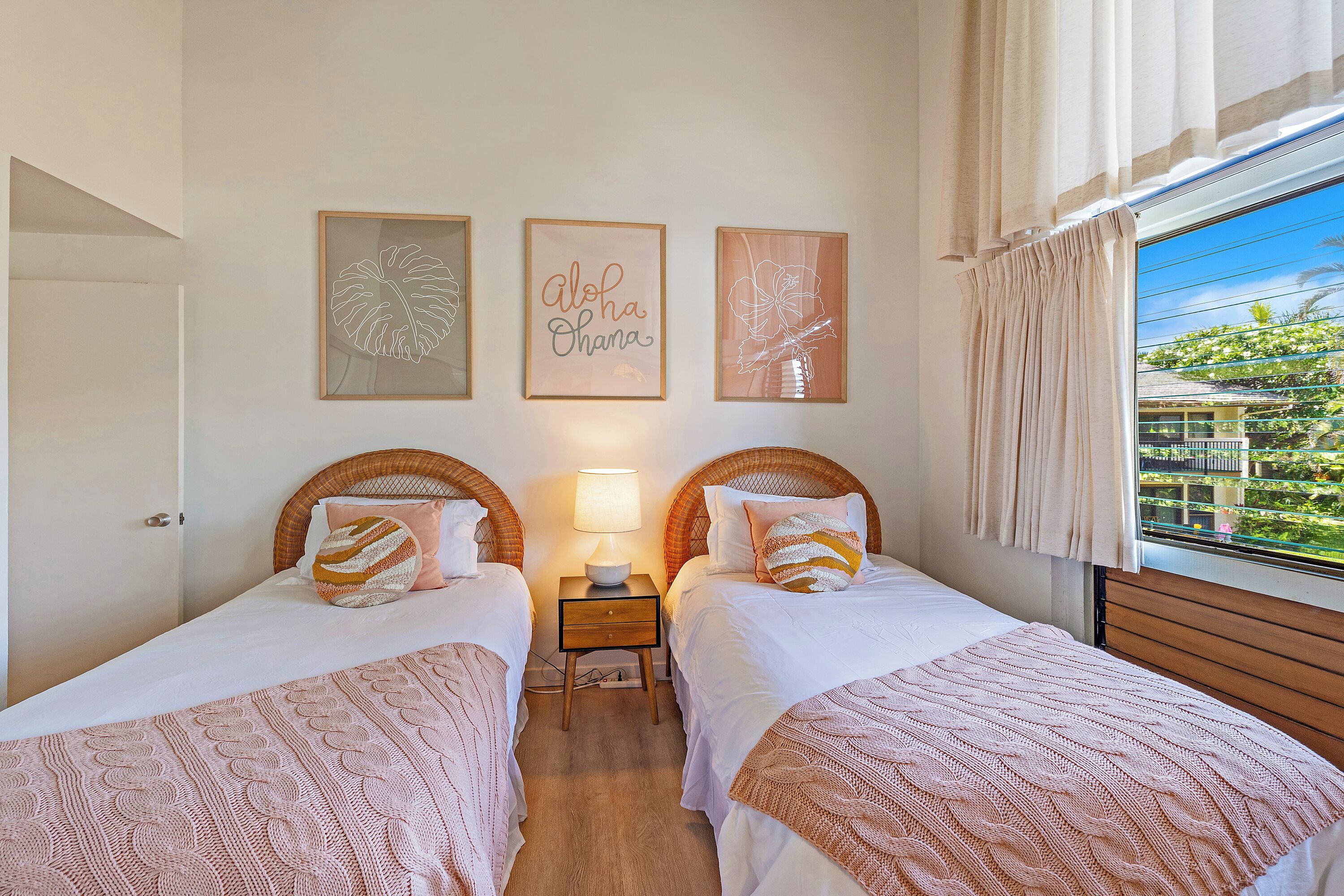 Een kamer met twee bedden, een nachtkastje met lamp en wanddecoratie.