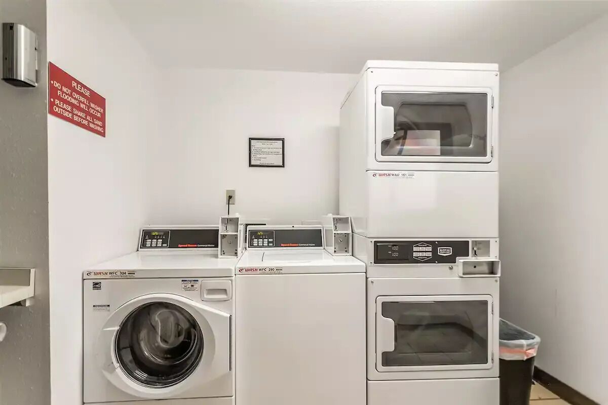 A laundry area with stacked washing machines and a red warning sign.
