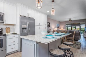 A modern kitchen with white cabinetry, a stainless steel refrigerator, and a marble countertop. - Walk to Everything! Beach, Nightlife & Heated Pool (Sarasota)