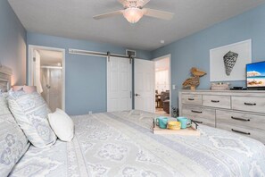 A bedroom with a bed, a dresser, a television, and a door leading to another room. - Walk to Everything! Beach, Nightlife & Heated Pool (Sarasota)