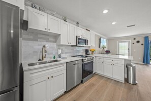 A modern kitchen with white cabinets, stainless steel appliances, and a tiled backsplash.