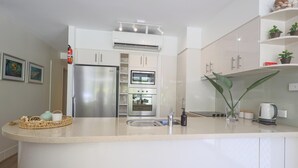 A modern kitchen with a central island, stainless steel appliances, and white cabinetry.