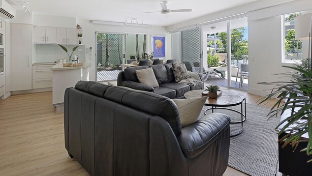 A modern living space with a sofa, a coffee table, and a dining area.