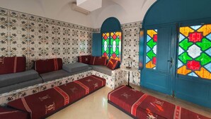 A room with a patterned wall, a blue door, and a bench with red cushions.