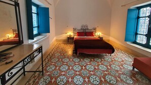 A bedroom with a bed, two bedside tables with lamps, a mirror, and a patterned floor.