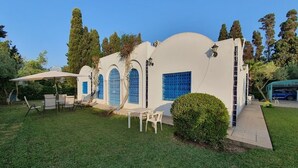 A white building with blue windows and a small patio area with chairs and a table.