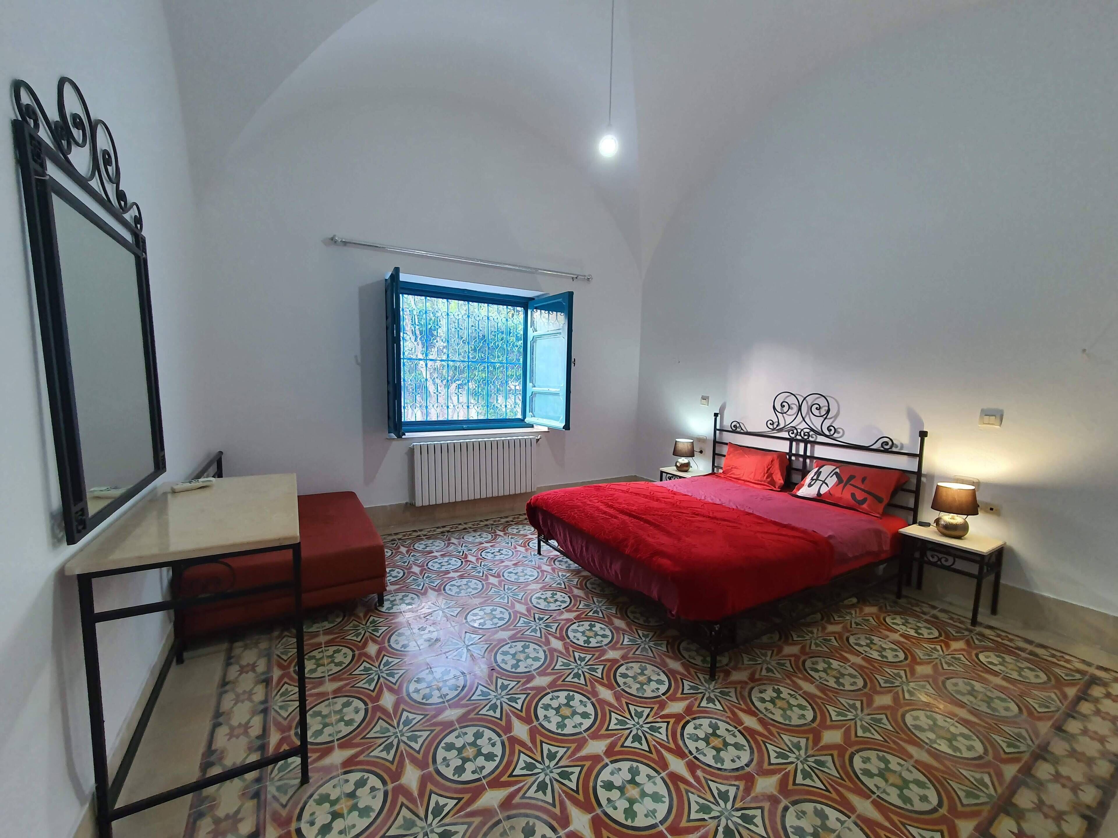 A bedroom with a bed, bedside tables, a window, and a radiator.