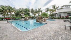A swimming pool with a stone feature, surrounded by palm trees and a paved deck. - GreenLinks/Updated Lely Condo; w/Office space-Lake Views-Resort Amenities (Naples)