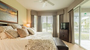 A hotel room with a large bed, a television, a ceiling fan, and a balcony with a view of palm trees. - GreenLinks/Updated Lely Condo; w/Office space-Lake Views-Resort Amenities (Naples)